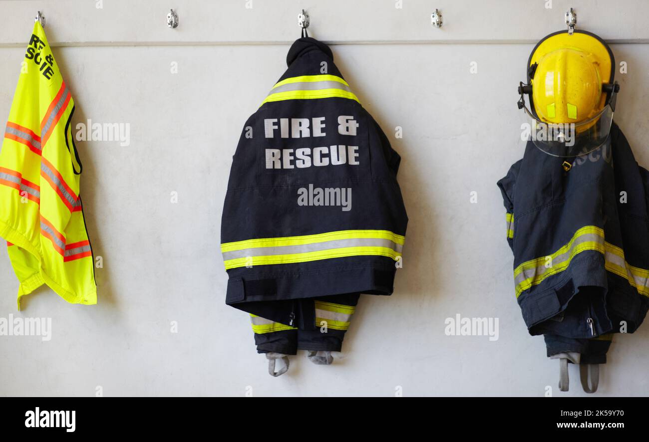 A firemans superhero costume. firemens clothing hanging from a wall. Stock Photo