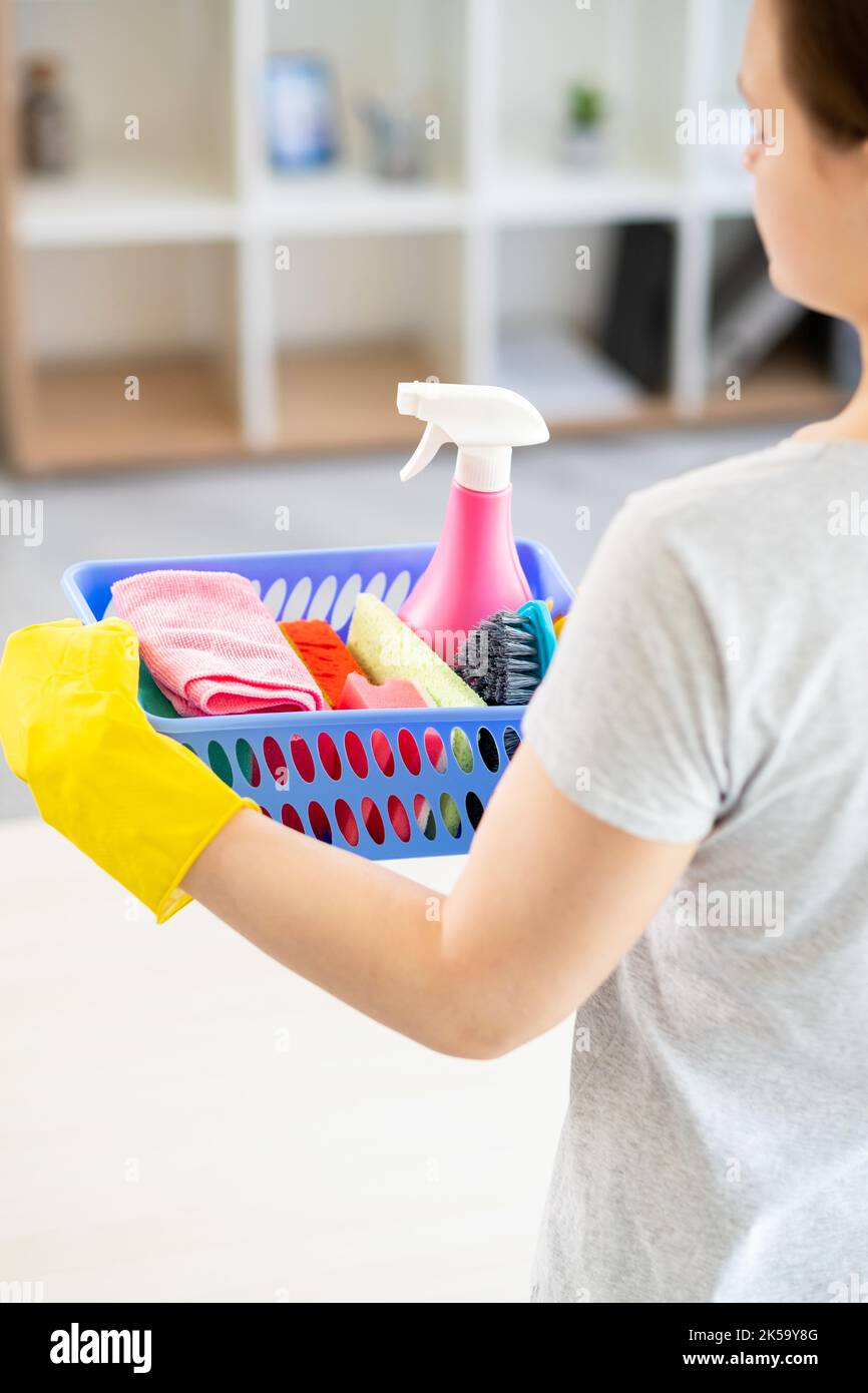 Cleaning service. Housework company. Home hygiene. Unrecognizable woman in protective gloves holding basket with cleaner spray soapy sponges brush mic Stock Photo
