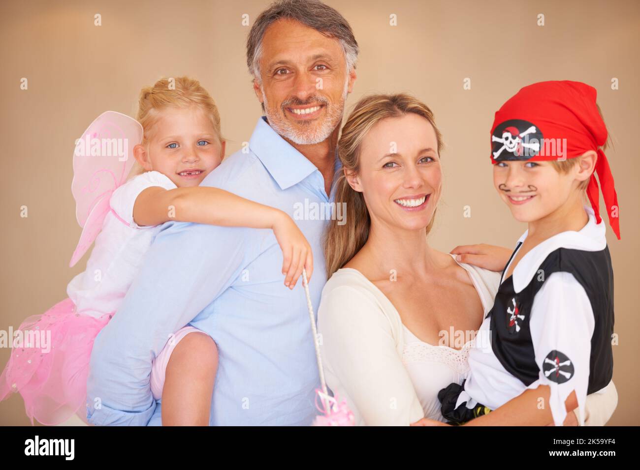 Portrait perfection. A family portrait of a father piggybacking his daughter and bother carrying her son on halloween. Stock Photo