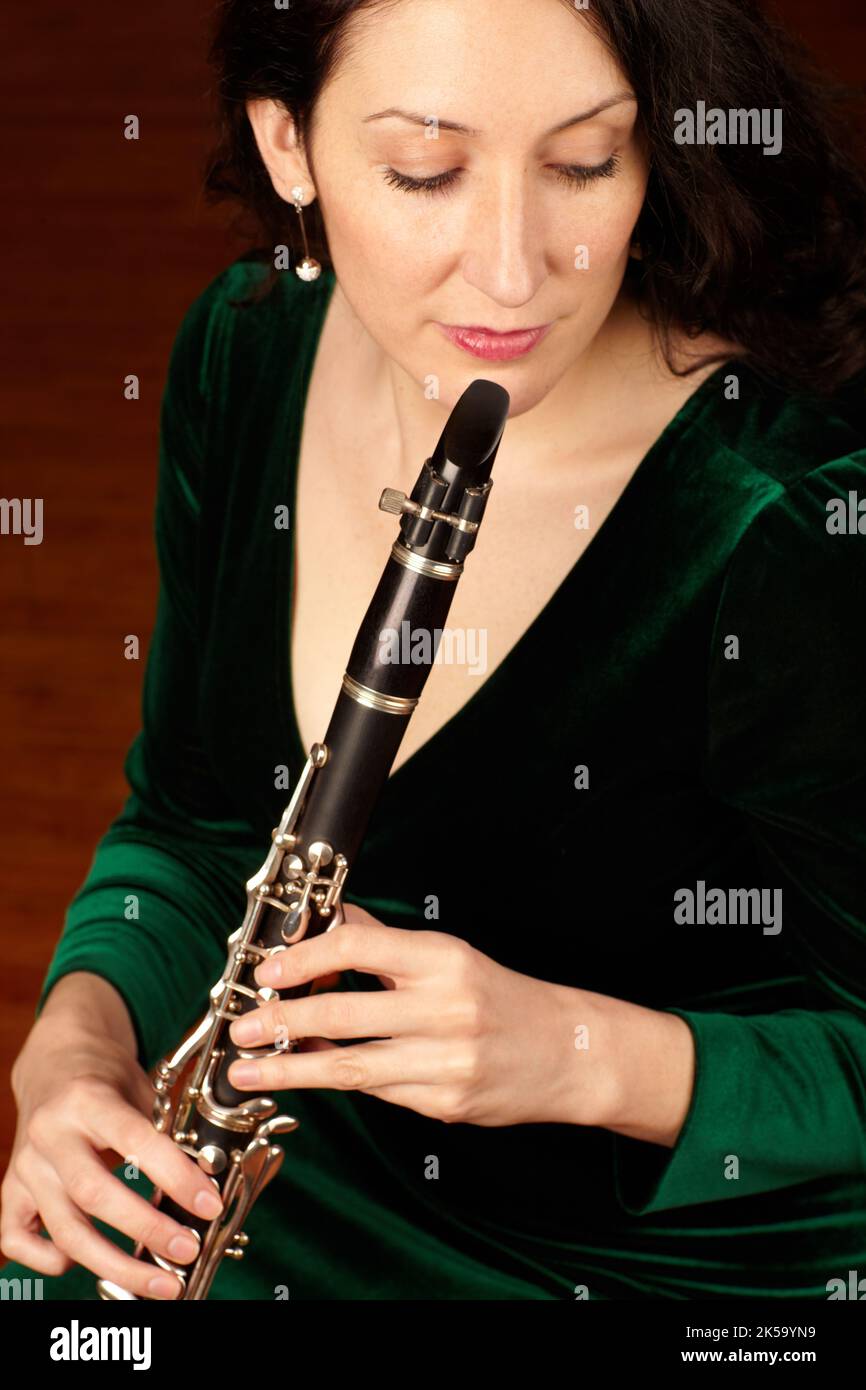 Her breath gives birth to beauty. A beautiful clarinetist sitting and playing her instrument. Stock Photo