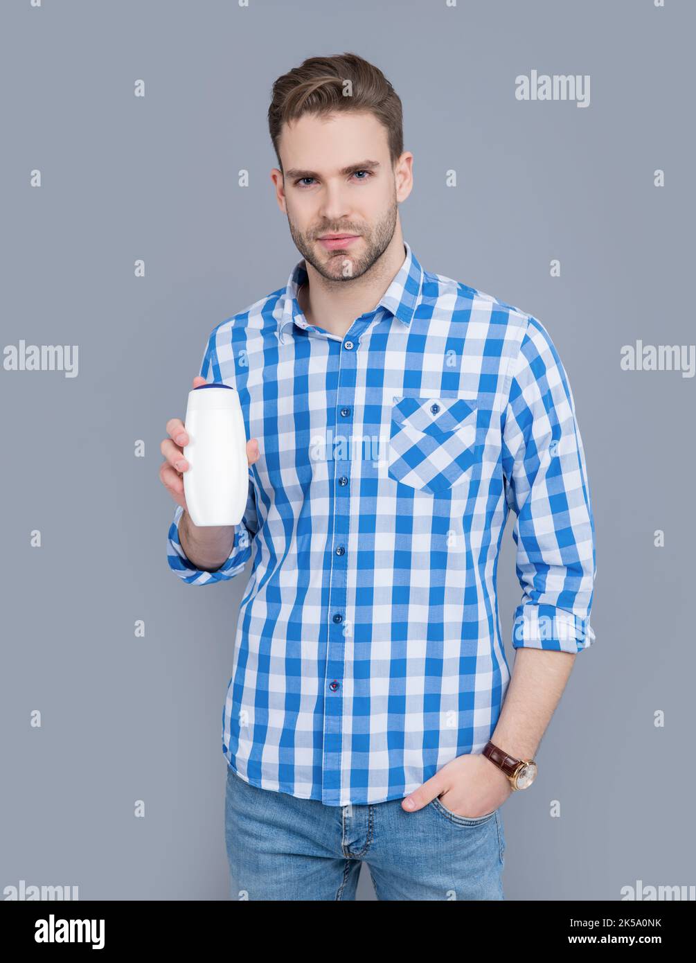 young guy hold bottle of aftershave product. guy hold aftershave