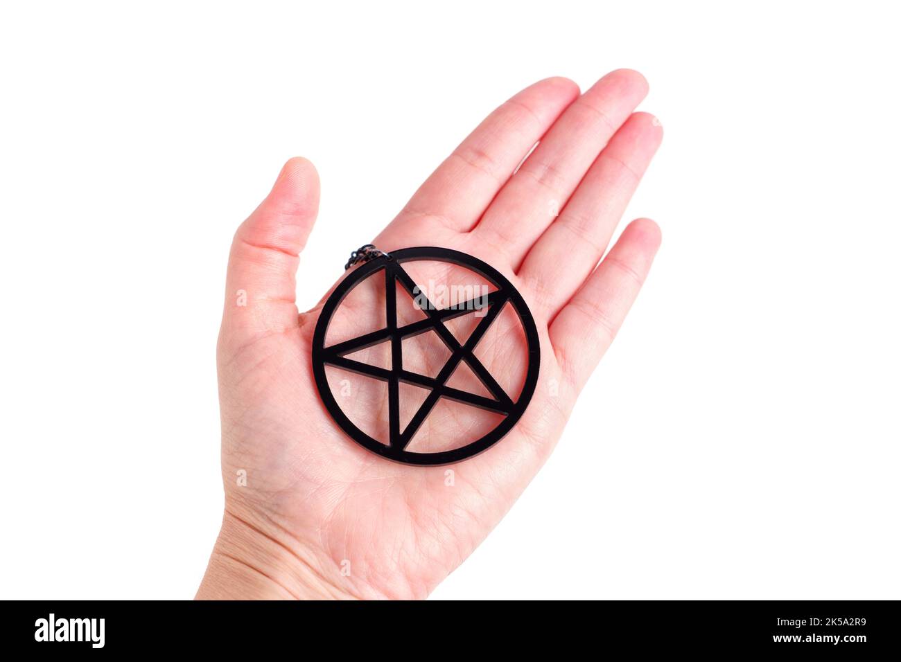 Large black pentagram shape placed on a hand palm isolated on white. Stock Photo