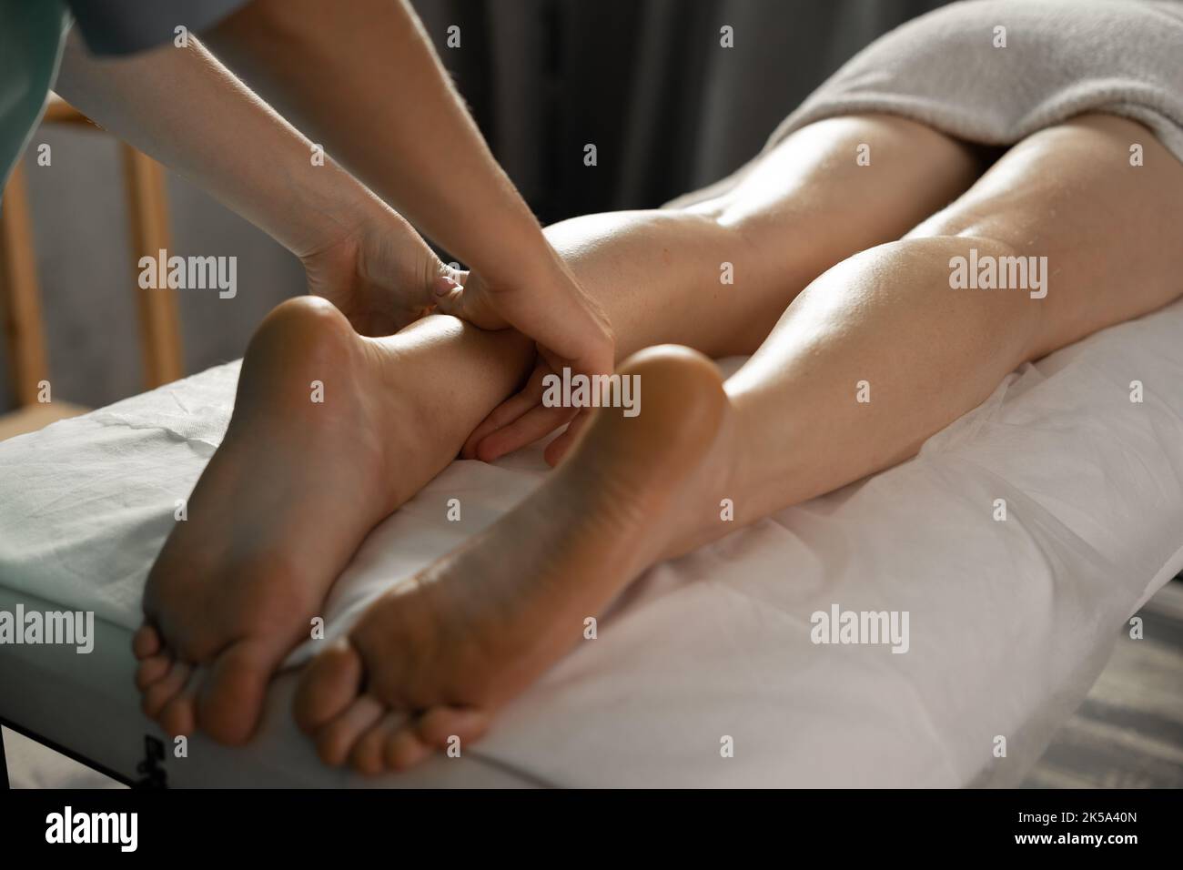 Young woman having feet and legs massage in beauty spa salon, close up. Massaging tired muscles. Stock Photo