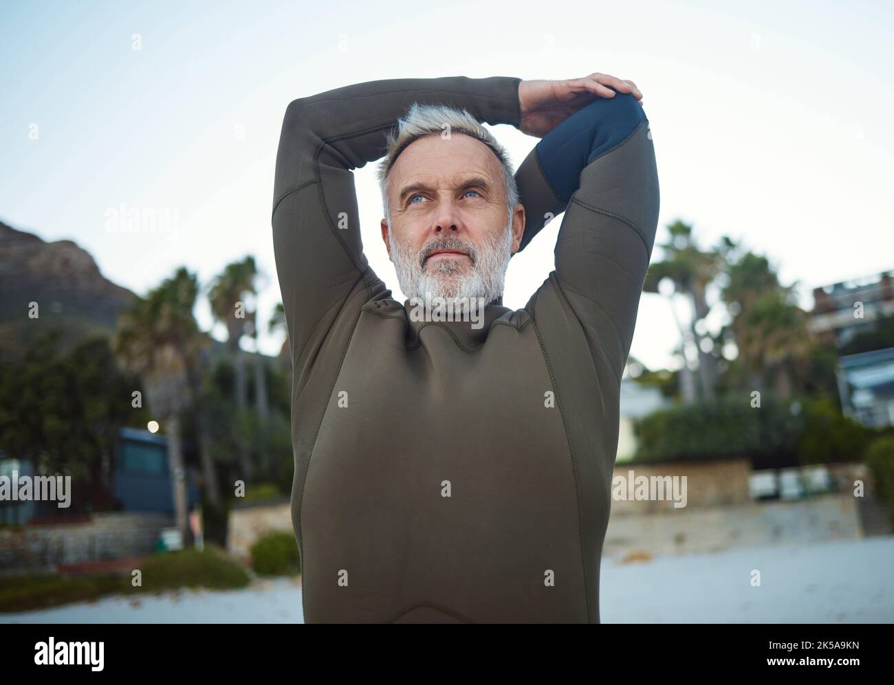 Surf, fitness and stretching with a sports man getting ready for