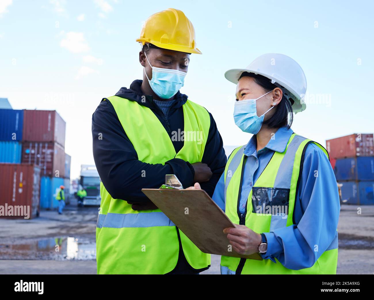 Logistics, shipping and team with mask for covid safety with a checklist for cargo inventory on a port. Export of delivery or supply chain management Stock Photo