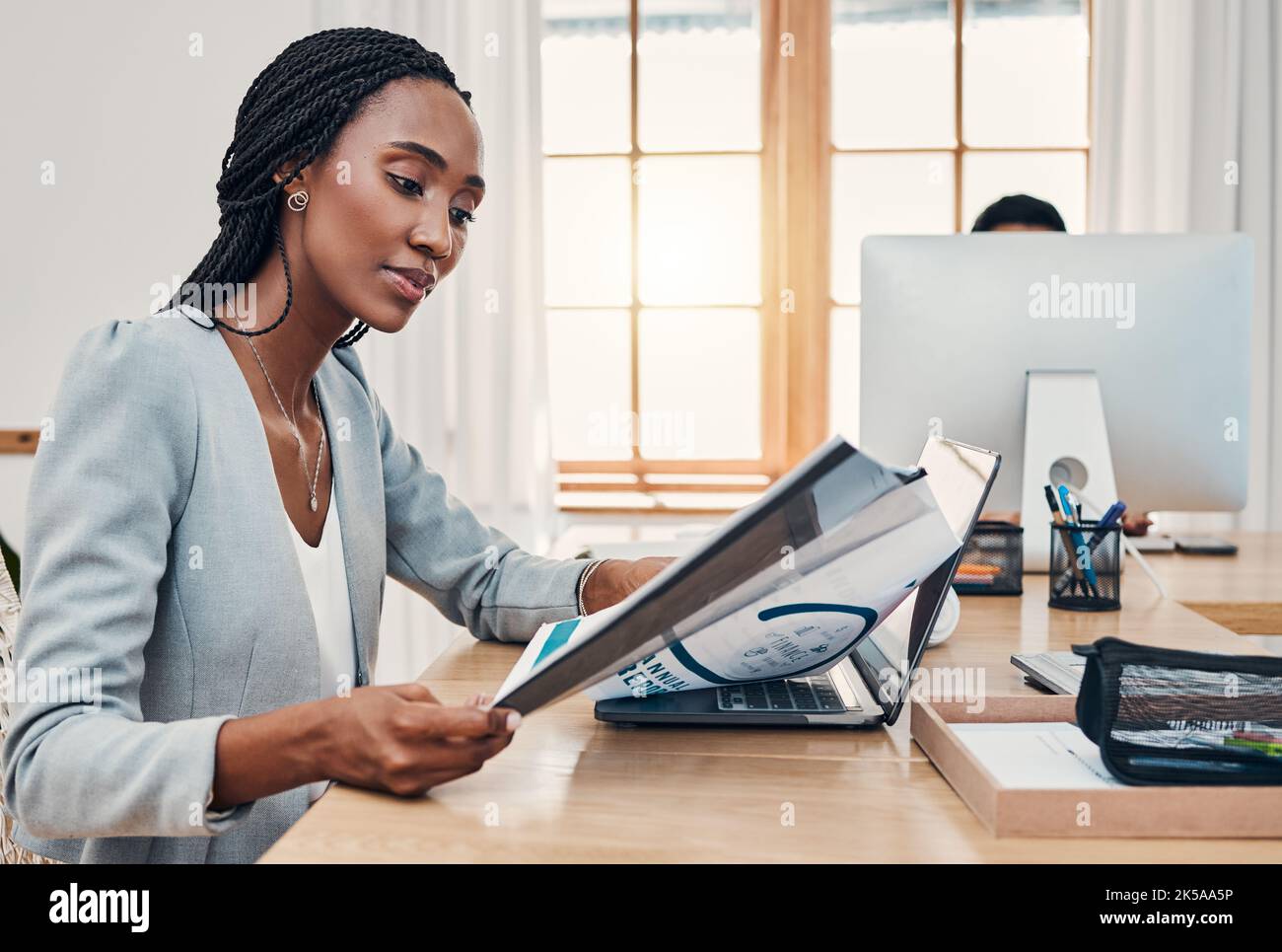 Black woman, office and report at desk reading with laptop for research, education or learning at work. Woman, training and paper with computer for Stock Photo