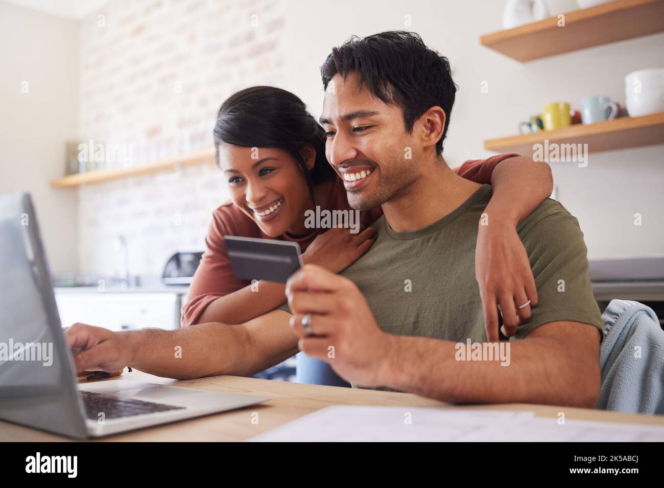 Ecommerce, happy online shopping and couple with credit card and laptop in kitchen in India. Computer, smile and man and woman making online payment Stock Photo