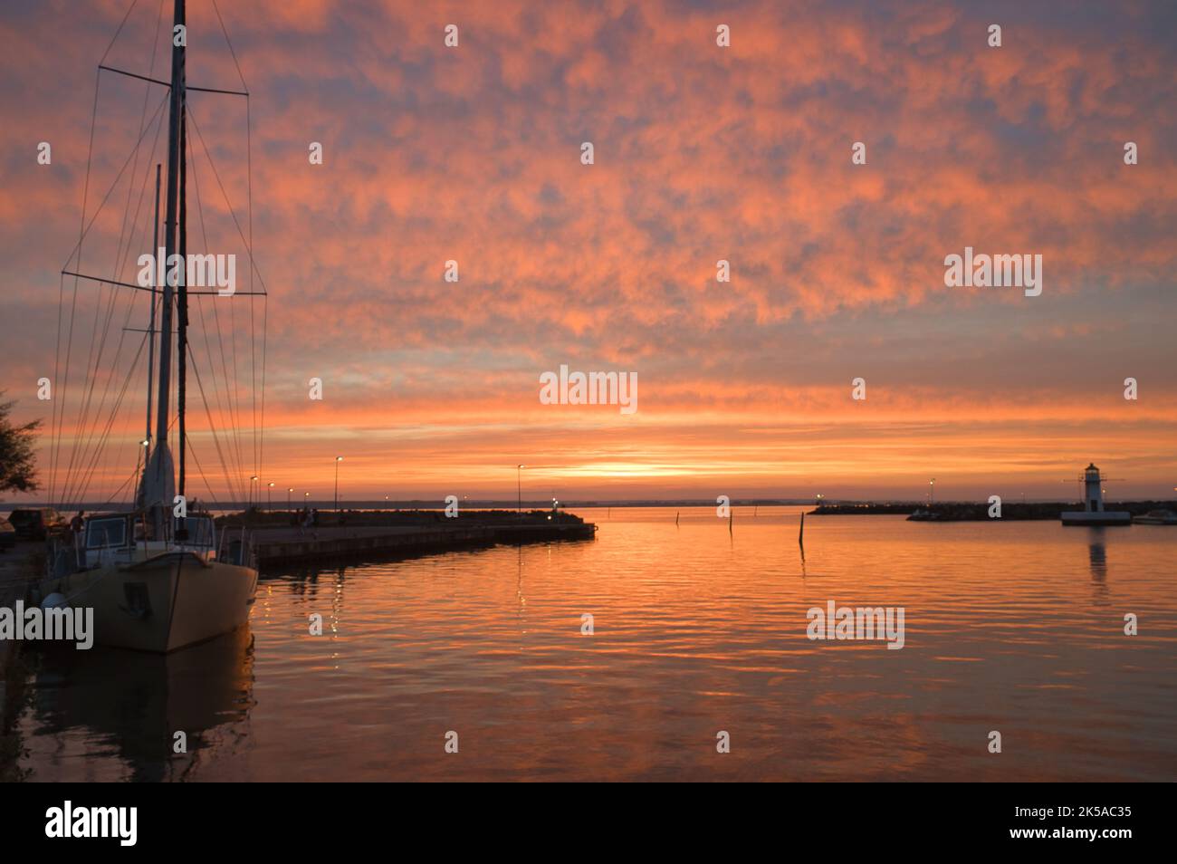 Sailing ship in the harbor of lake Vaettern at sunset. Lighthouse in ...