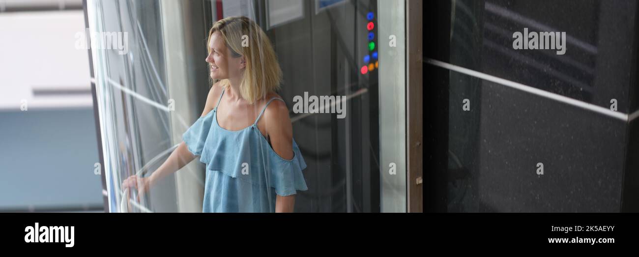 Young smiling woman riding in transparent glass elevator Stock Photo Alamy