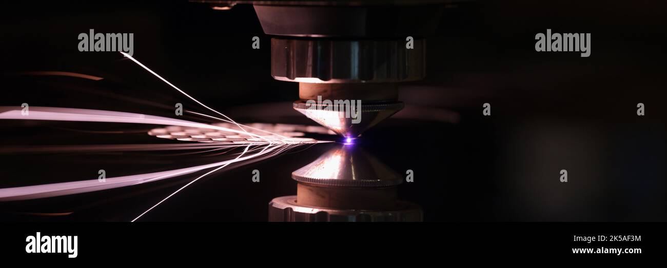 Laser machine cutting sheet of metal with bright sparks closeup Stock Photo