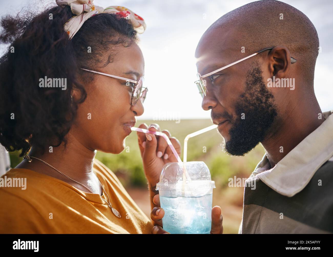 Love, share and drink with straw and couple in nature for travel, countryside and sunset date on Madrid vacation. Happy, summer and romance with black Stock Photo