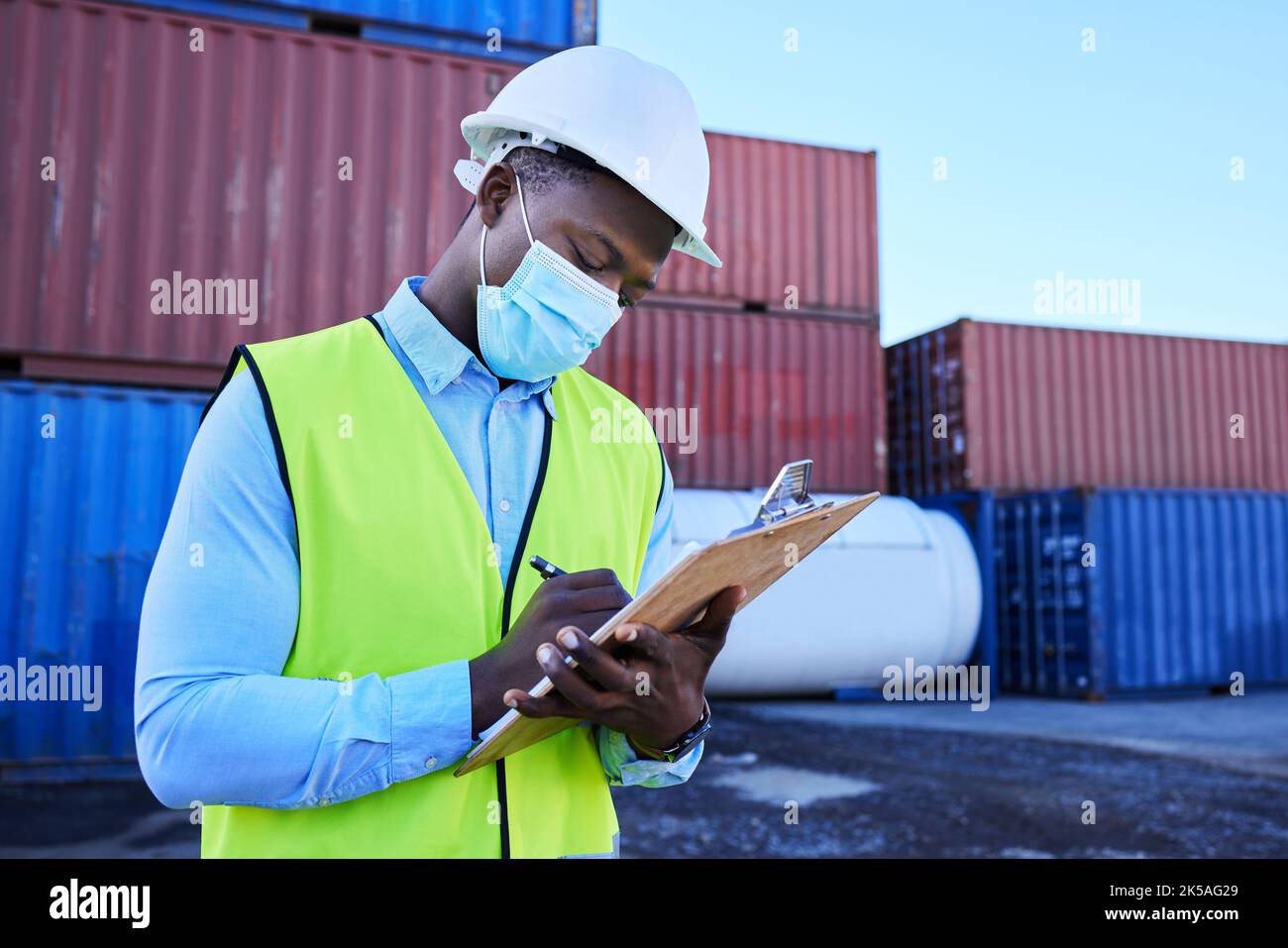 Black man working in covid with face mask, shipping container in supply chain industry and logistics stock inventory. Healthcare safety in export Stock Photo