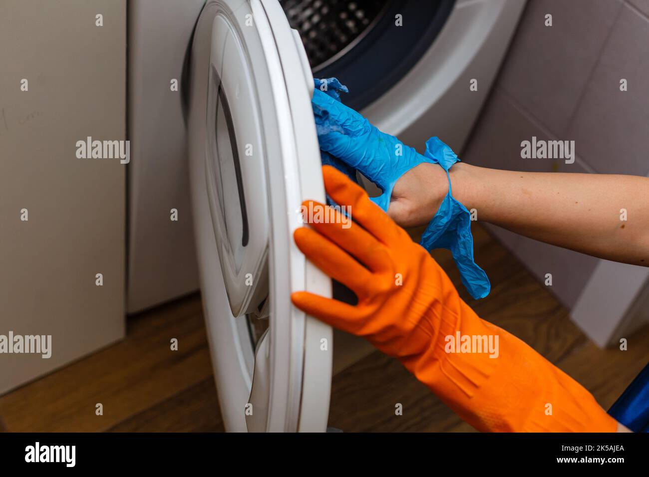 Hand in torn glove cleaning the washing machine. Regular clean up. Maid