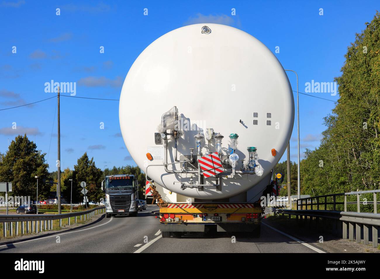 Rear view of oversize load transport of LNG storage tank on highway bridge, truck from opposite direction takes caution. Salo, Finland. Sept 22, 2022. Stock Photo