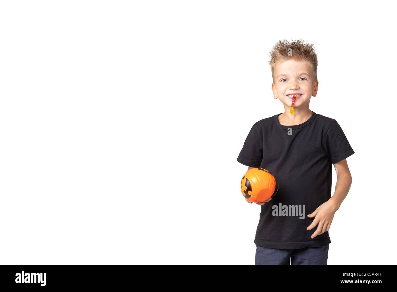 Halloween kids boy with pumpkin buckets eating candy on a white studio background, banner, copy space. Ready for trick or treat holiday. Stock Photo