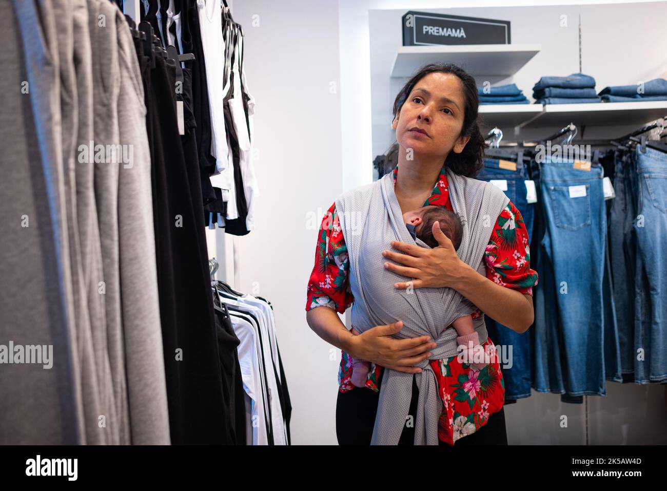 A woman carrying her kid seen shopping inside a clothing store in the ...