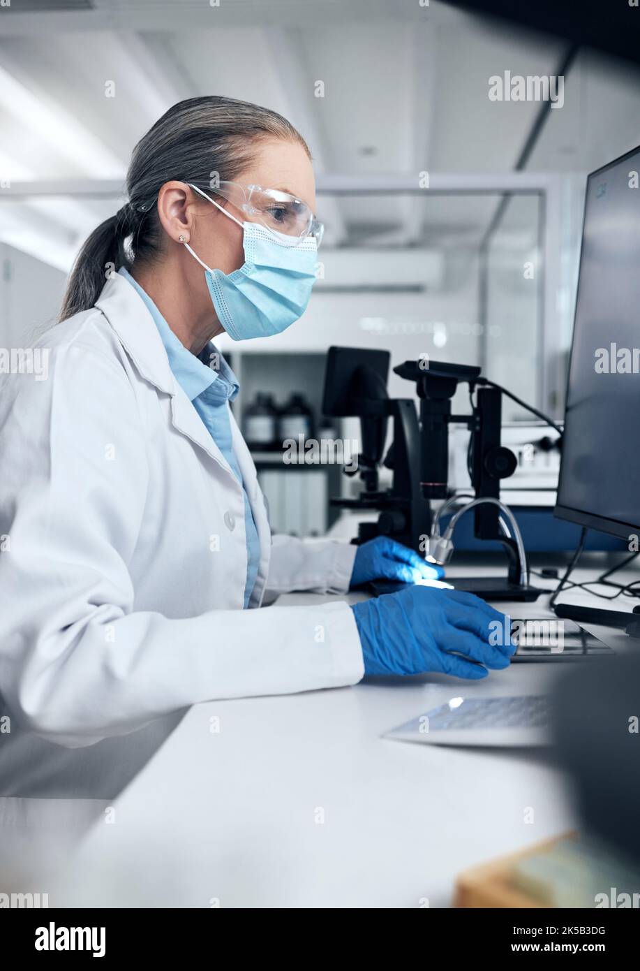 Science woman, covid and computer laboratory research, medical innovation and expert test online. Senior scientist mask, desktop data and vaccine Stock Photo