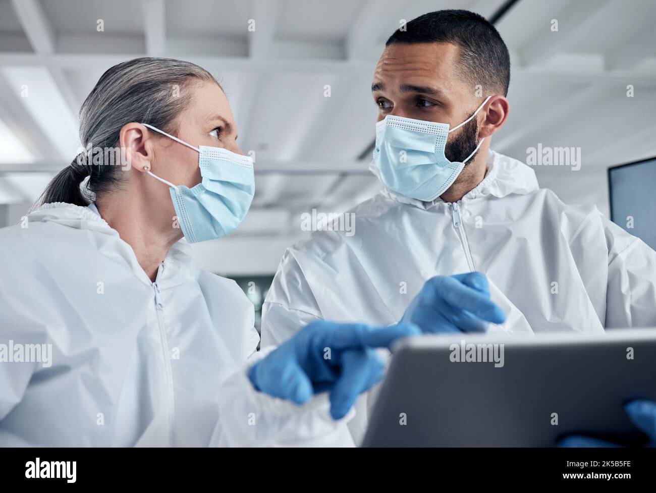 Scientist team, covid research and tablet with doctors discussing medical information, analysis and teamwork in lab. Medical man and woman using Stock Photo