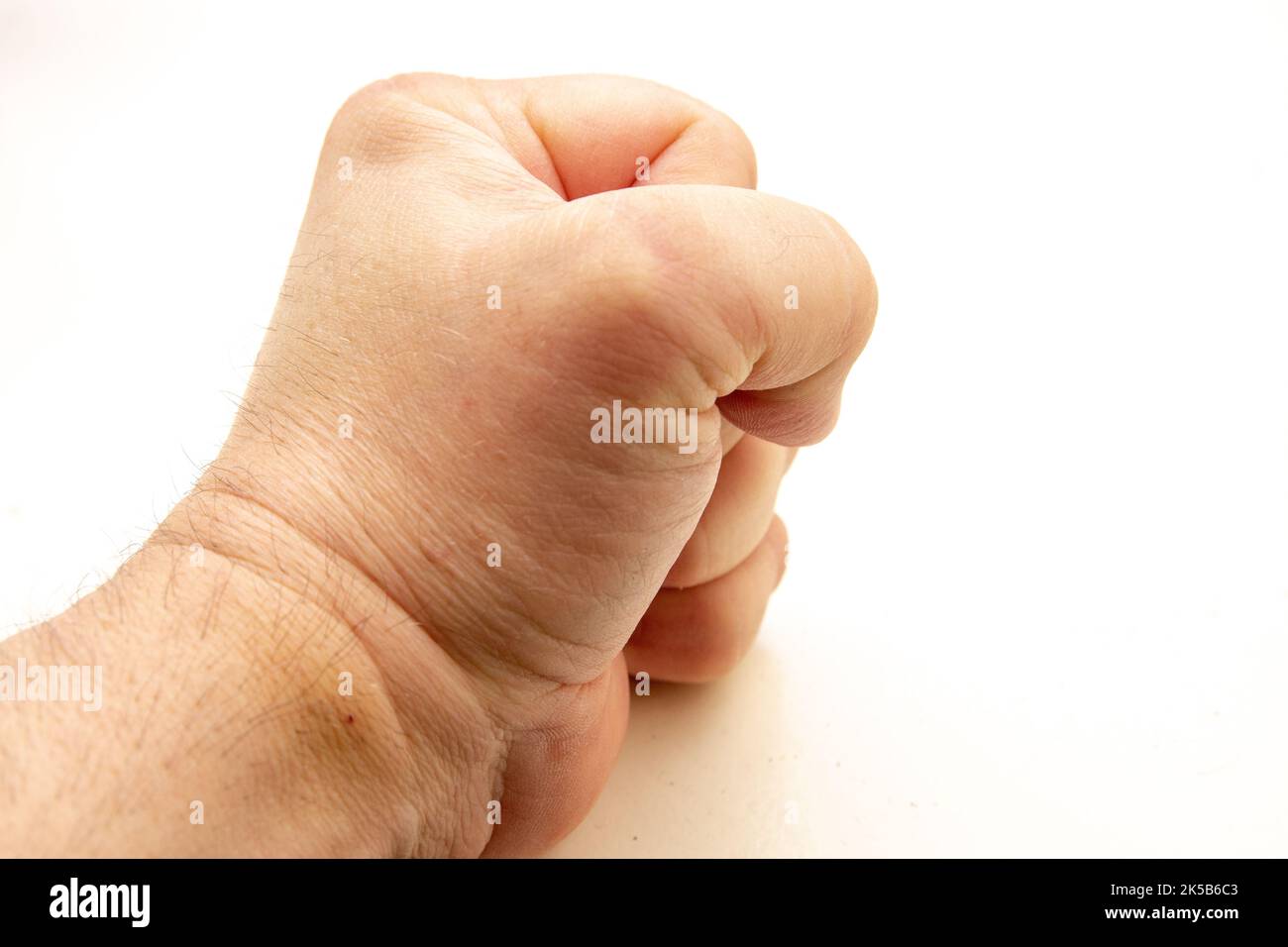 A fist of a person banging on a table Stock Photo
