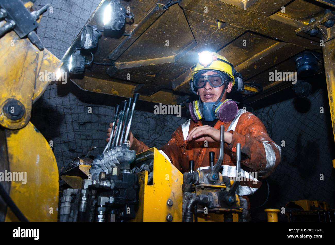 Miner operating a Jumbo Drill in an underground mine Stock Photo