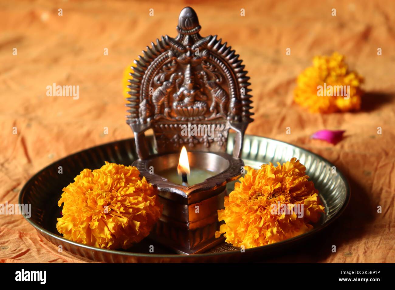 Lit oil brass Goddess Lakshmi /Gajalakshmi vilakku in a copper plate with marigold flowers/Diwali/Deepavali festival Stock Photo