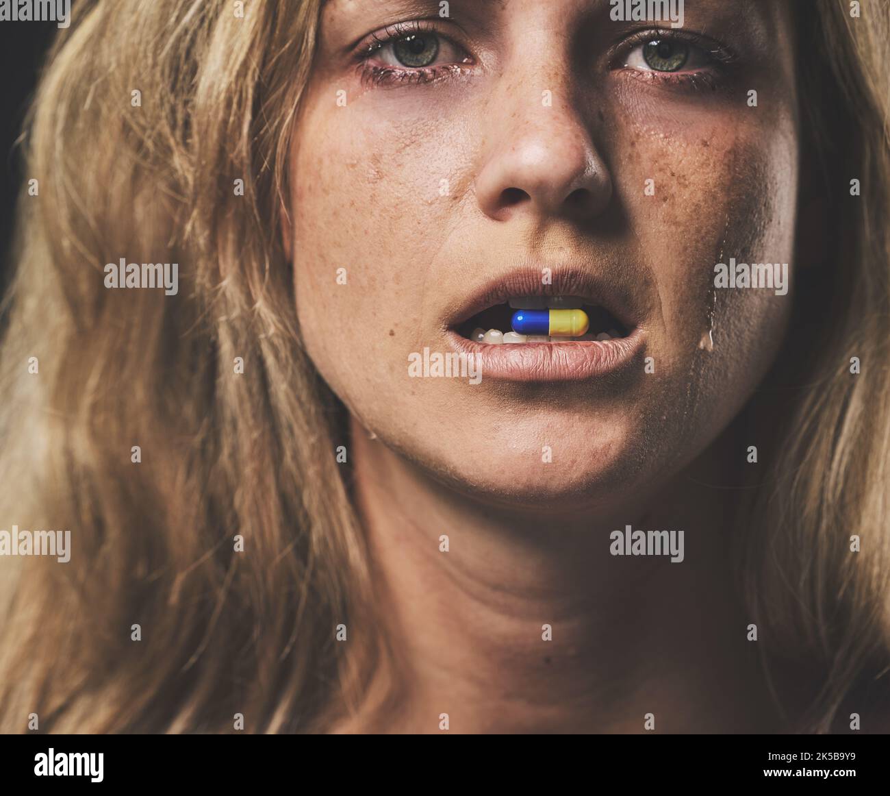 Depression, portrait and girl with pill in her mouth with emotional tears on face from crying. Sad, unhappy and isolated woman with mental health Stock Photo
