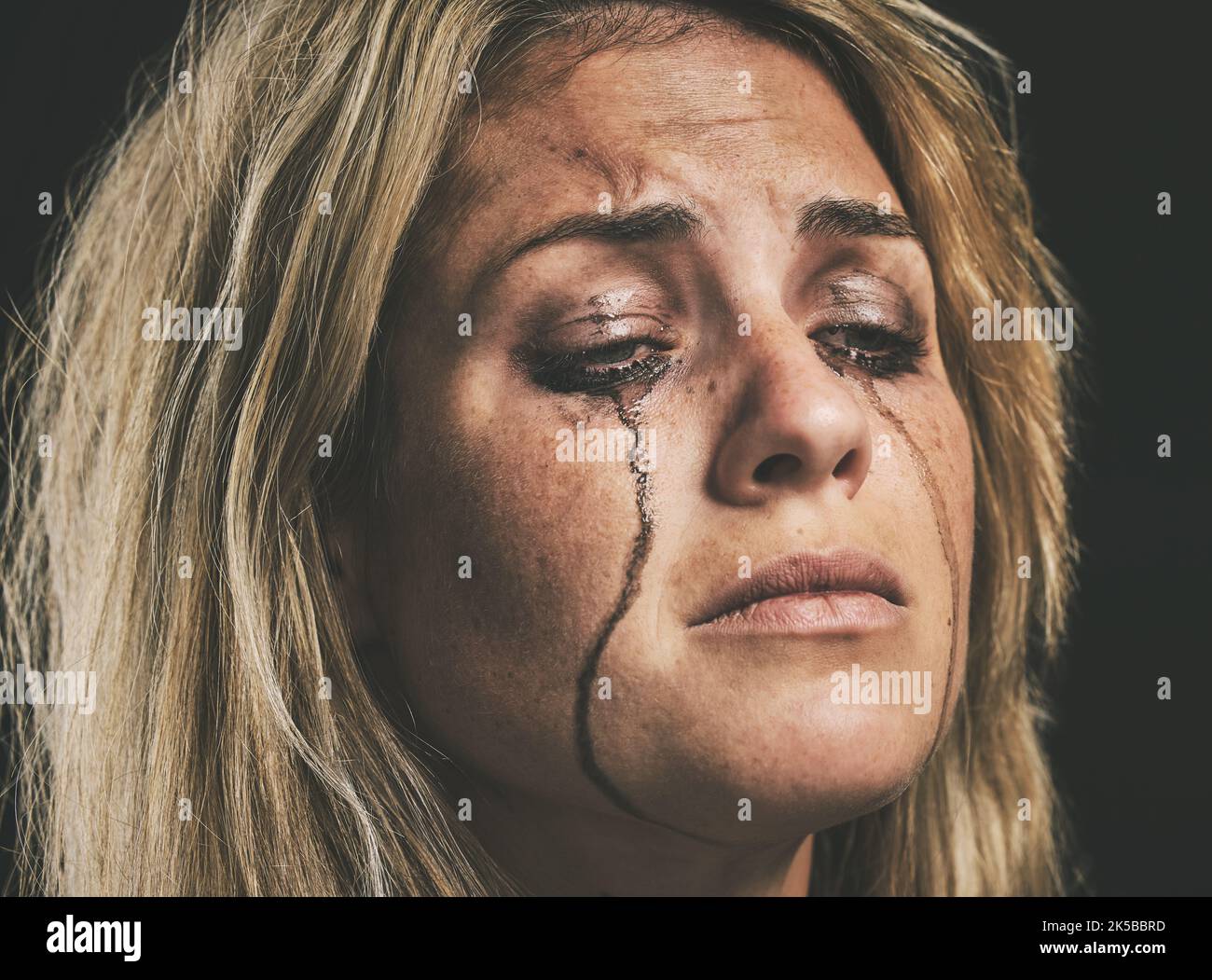 Sad, depression and woman crying with makeup smudge on face from tears with studio wall closeup. Depressed, hopeless and unhappy girl with mental Stock Photo