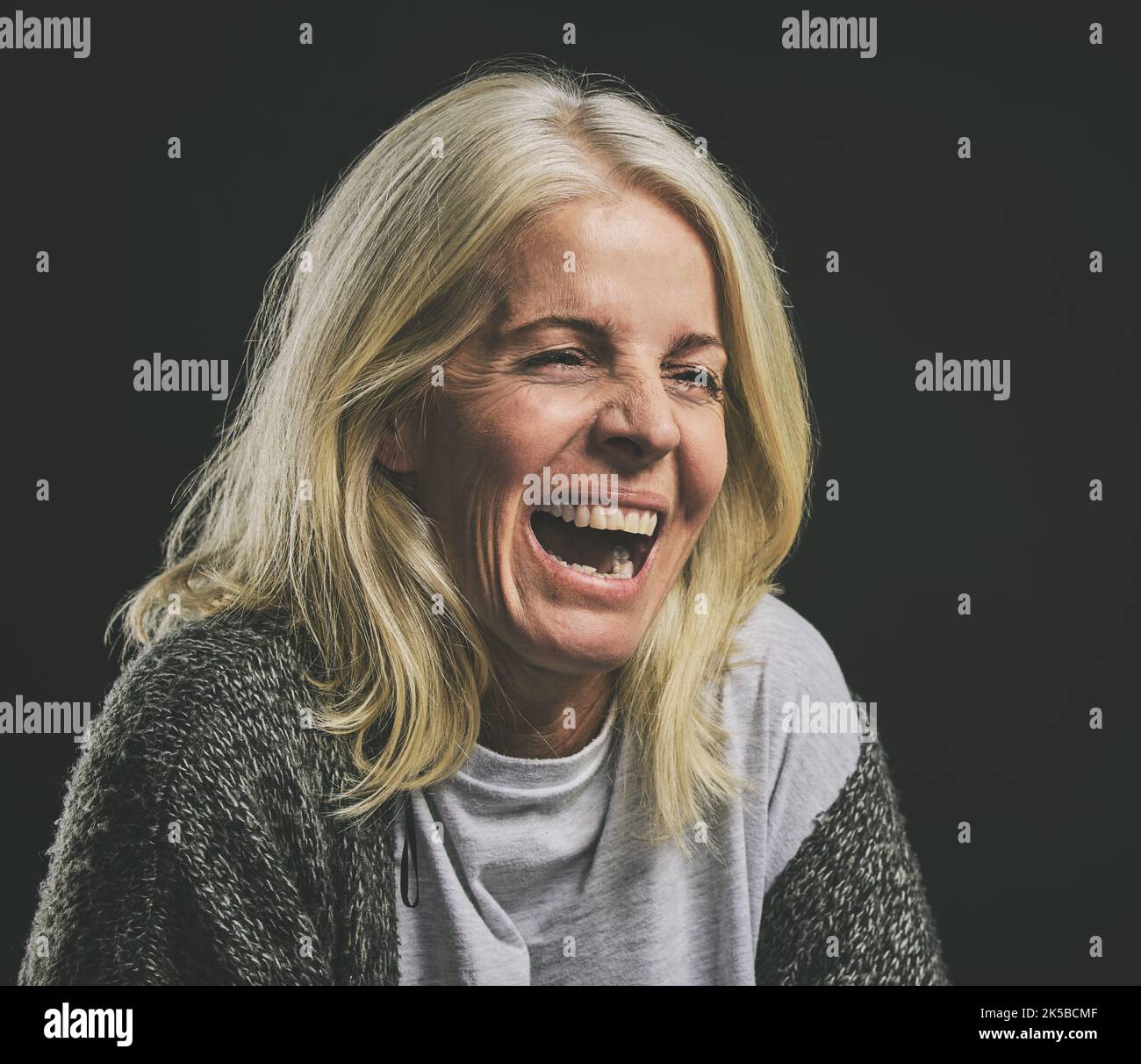 Mental health, depression and woman with bipolar laughing in dark studio. Lady with schizophrenia, anxiety and mental illness with laugh expression Stock Photo