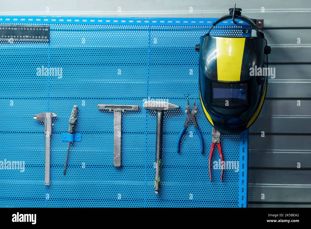 welding mask hanging on a stand with tools Stock Photo