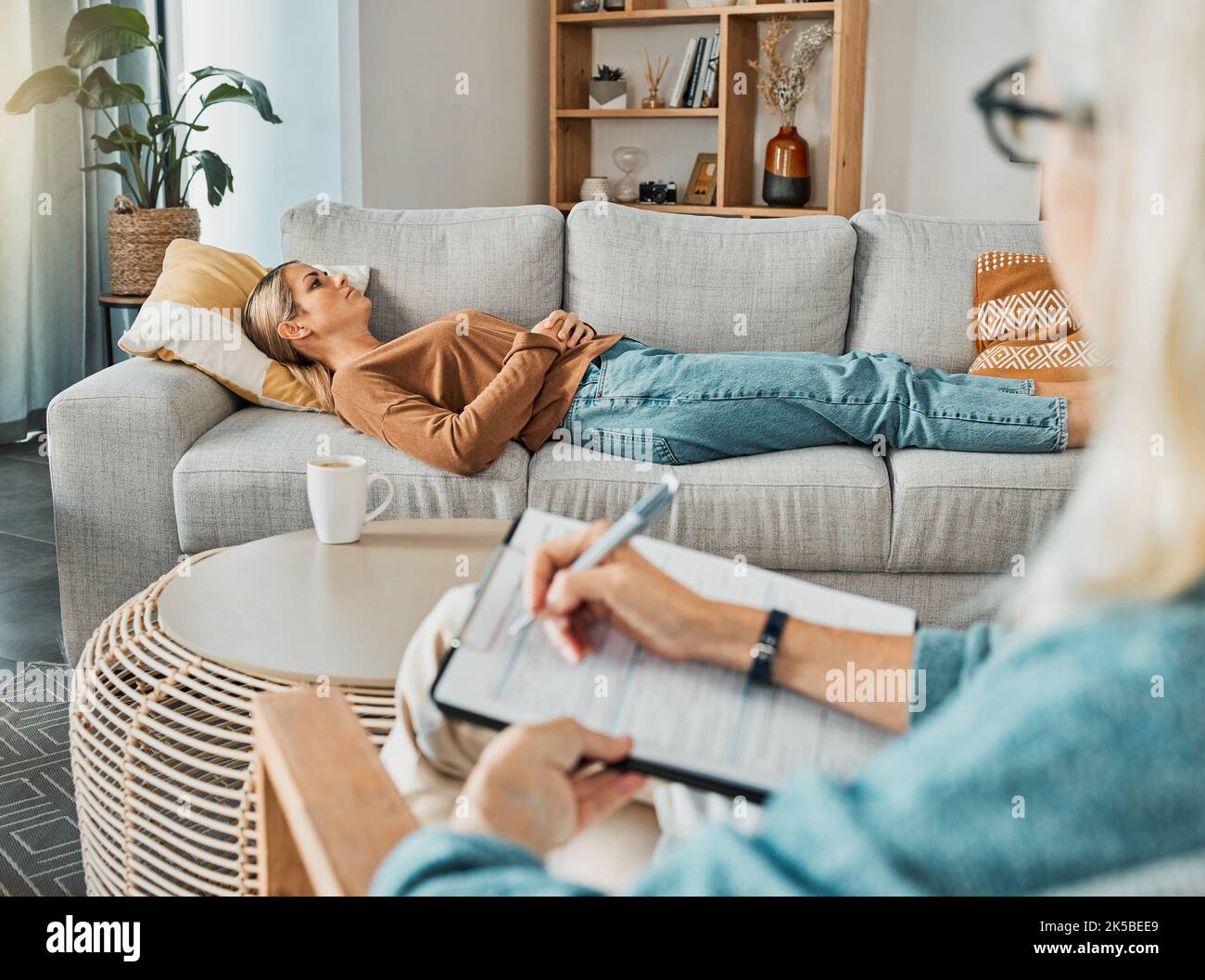 Relax, psychology and therapist with woman patient struggling with depression resting on sofa. Professional psychologist analysis notes for Stock Photo