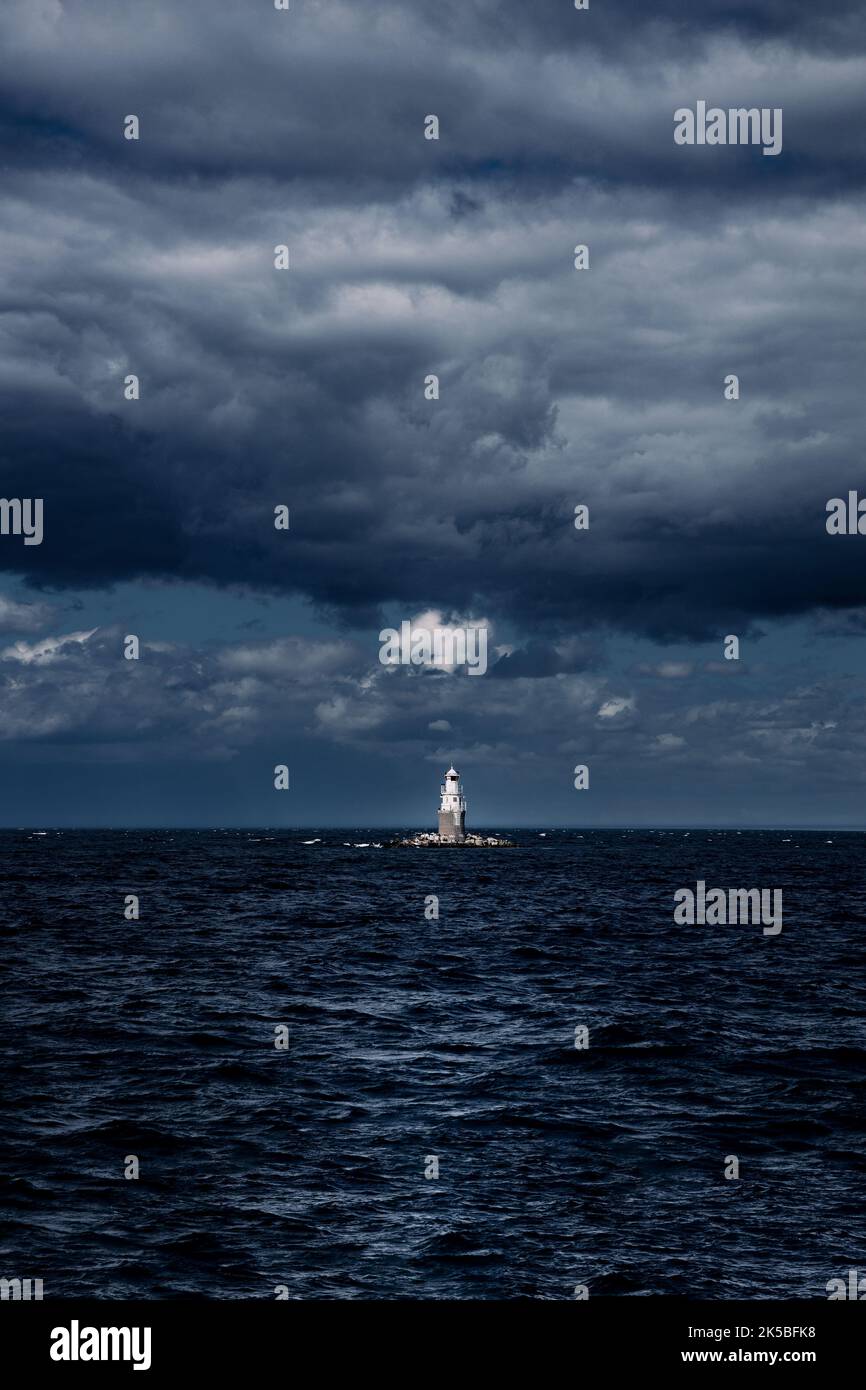 A lighthouse standing in the middle of a stormy ocean under dark clouds ...