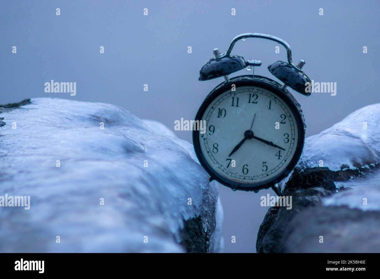 Frozen time. A clock frozen in ice. Extreme weather situation. Daylight