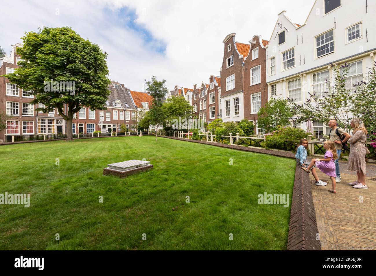 Young family visits the beguinage in the center of Amsterdam. The begijnhof is one of the oldest courtyards in Amsterdam. Stock Photo