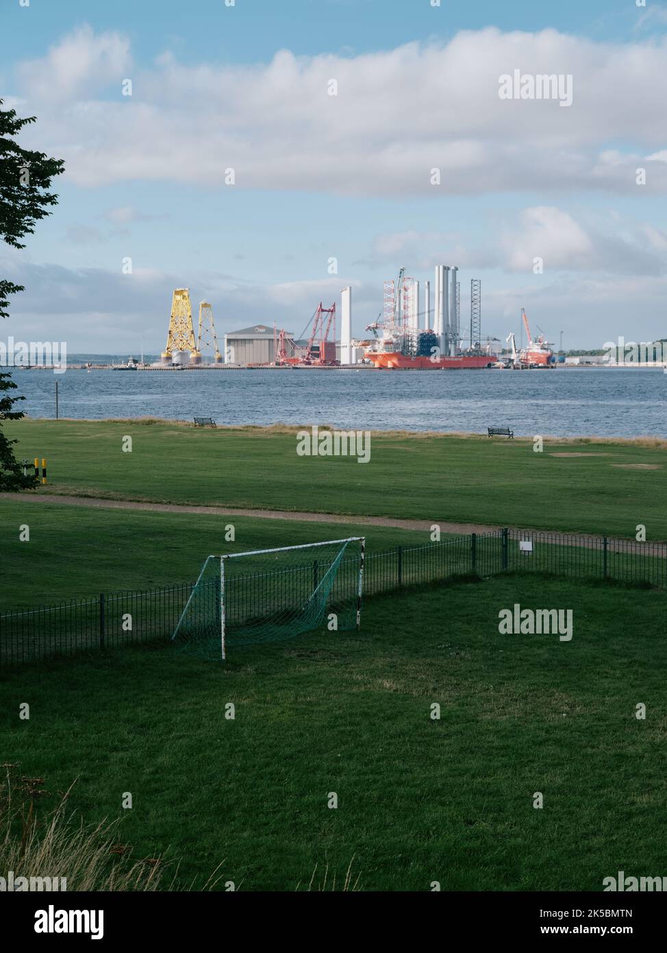 A lone football pitch goal and distant wind turbine factory in Cromarty, Black Isle, Ross & Cromarty, Highland, Scotland UK Stock Photo