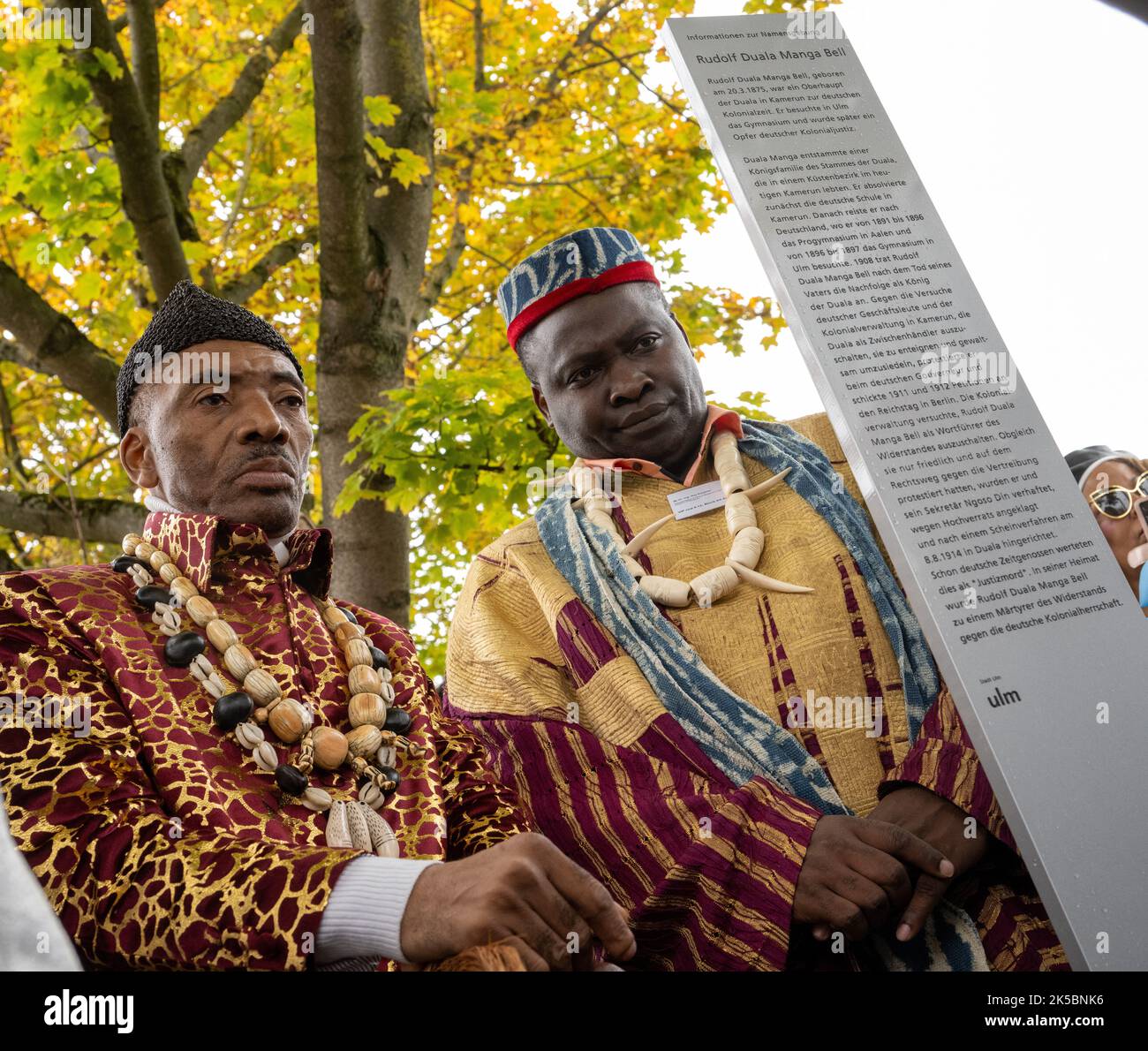 Ulm, Germany. 07th Oct, 2022. King Jean-Yves Eboumbou Douala Bell (l) from Cameroon stands with Guy. Klouemo, representative of the King of Bangoua, next to a stele. By naming the square near the new justice building, the city commemorates Rudolf Duala Manga Bell, who went to school in Ulm for a few years at the end of the 19th century before returning to his homeland and - as king of his people - being executed by the German colonial administration in 1914 after a mock trial. Credit: Stefan Puchner/dpa/Alamy Live News Stock Photo