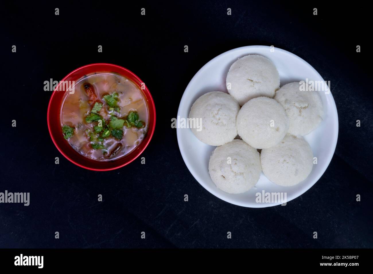 Idly In White Plate With Sambar In Red Bowl, Isolated On Black Background, Idly In White Plate, Sambar In Red Round Bowl, South Indian Breakfast Stock Photo