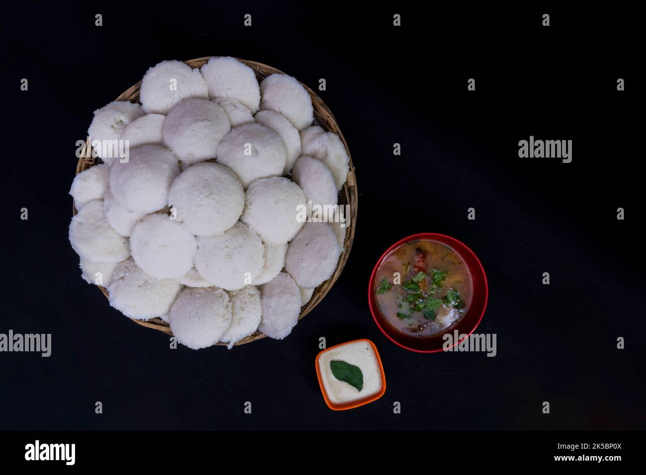 South Indian Breakfast, Idly In Stick Bowl Sambar with Coconut Chutney, Isolated On Black Background, Idly In Stick Bowl, Sambar In Red Round Bowl Stock Photo
