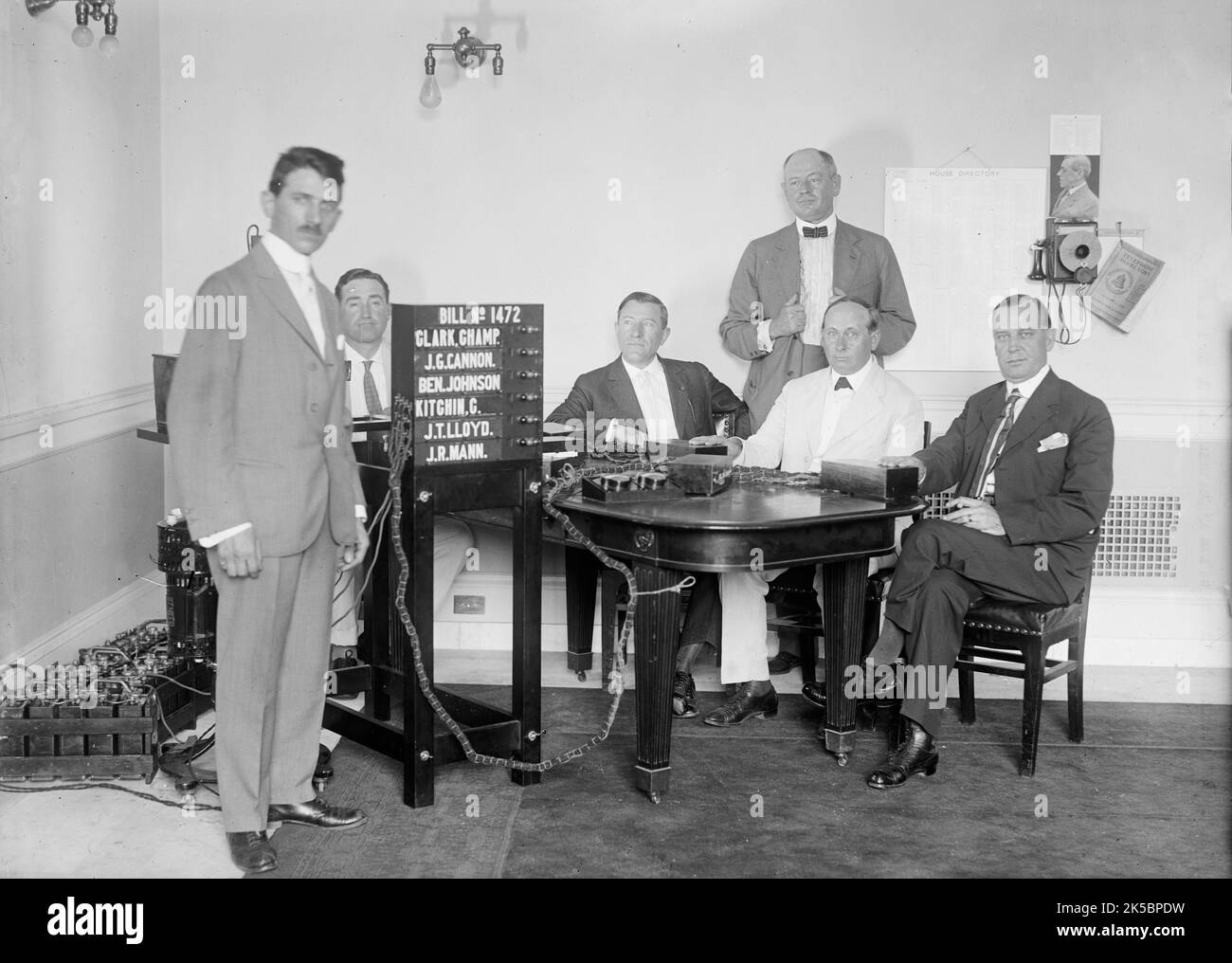 Bobroff Voting Machine - Being Considered For Use In House, 1917. Standing right to left: Representatives Jacoway; Caraway; and Britten. Sign reads: 'Bill no. 1472 - Clark, Champ [James Beauchamp Clark]; J.G. Cannon; Ben. Johnson; Kitchin, C.; J.T. Lloyd; J.R. Mann'. To the right of the sign are seated US politicians Frederick Albert Britten, Thaddeus Horatius Caraway and Henderson Madison Jacoway. Stock Photo