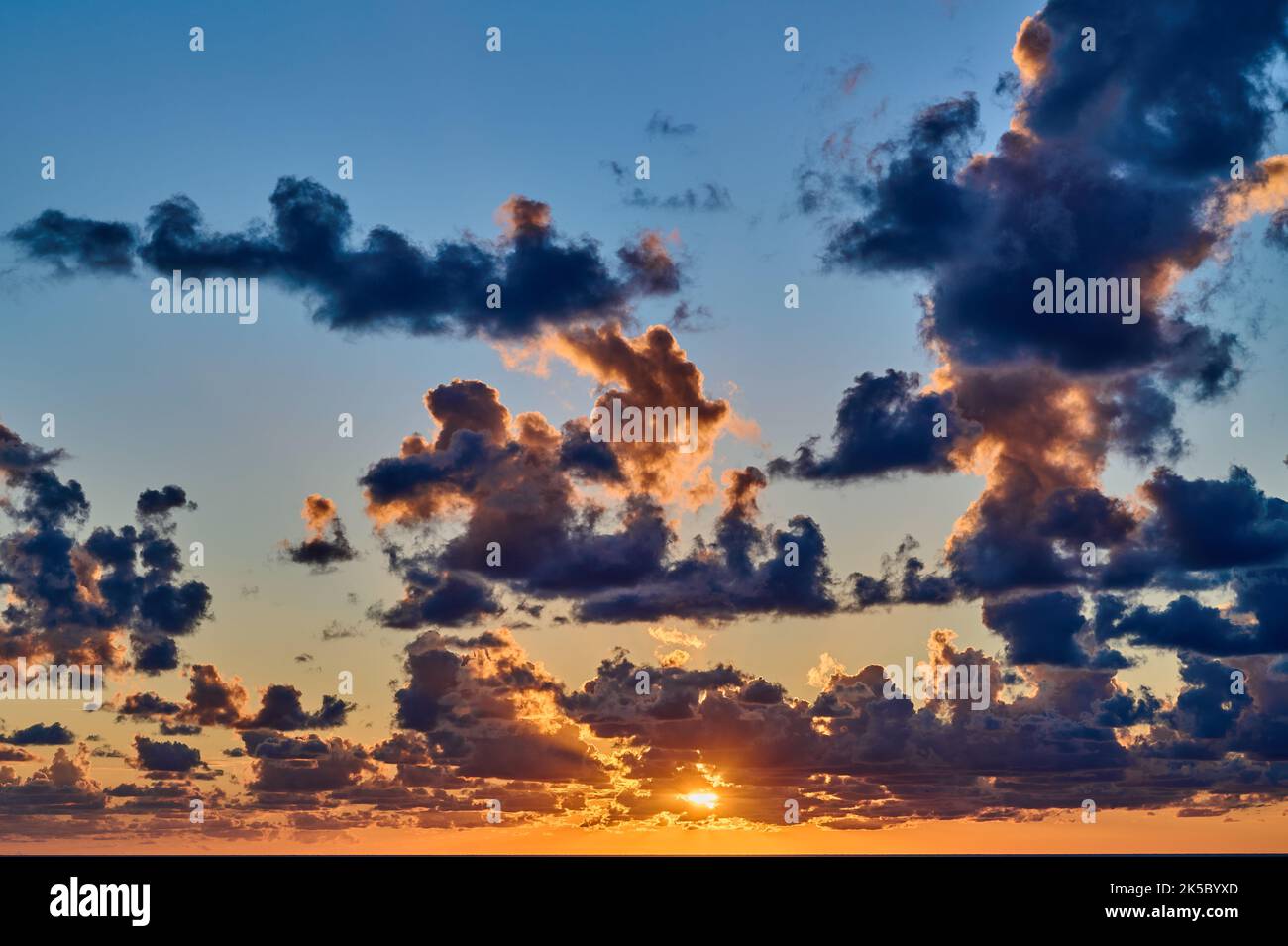 Sunset with dramatic clouds and blue sky over the sea Stock Photo - Alamy