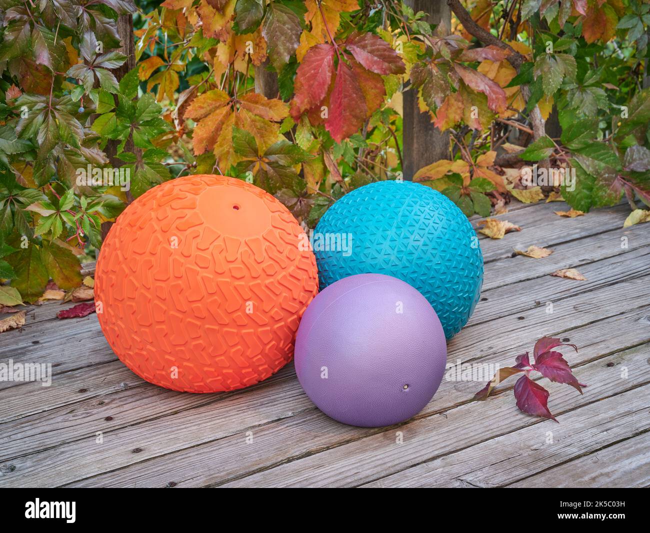 three heavy slam balls filled with sand on a backyard deck with fall