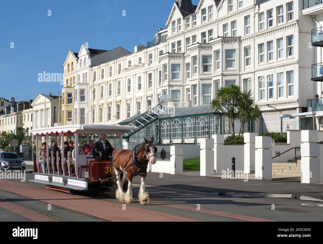 A horsedrawn carriage passes by an elegant hotel on Douglas promenade