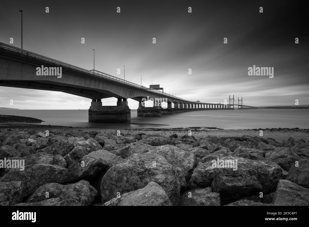A black and white photograph of the Prince of Wales Bridge between England and Wales over the Severn Estuary from Severn Beach, Gloucestershire, England. Stock Photo