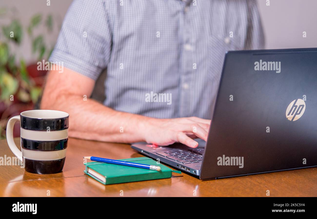 Man sitting at a desk typing on a laptop Stock Photo