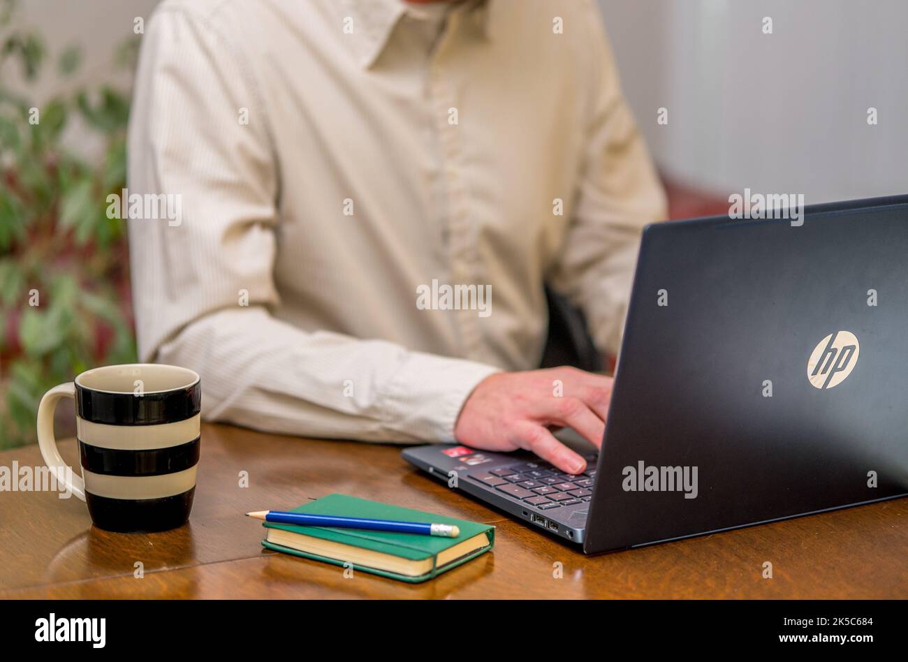 Man sitting at a desk typing on a laptop Stock Photo