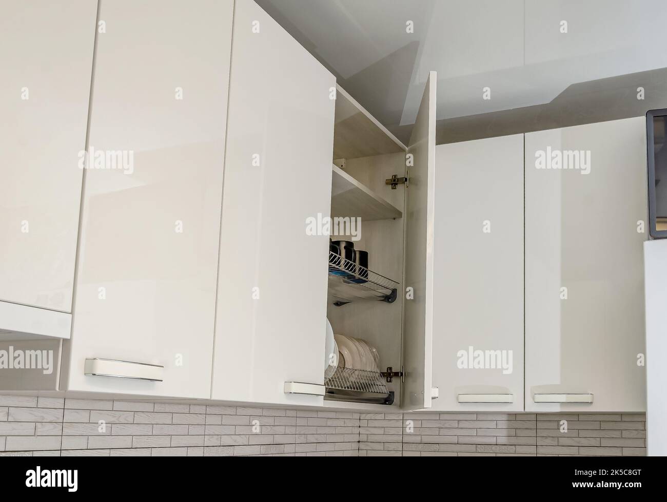 An upper kitchen cabinet with open door Stock Photo