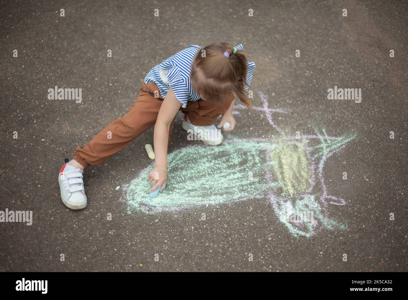 Child draws on asphalt with chalk Stock Photo - Alamy