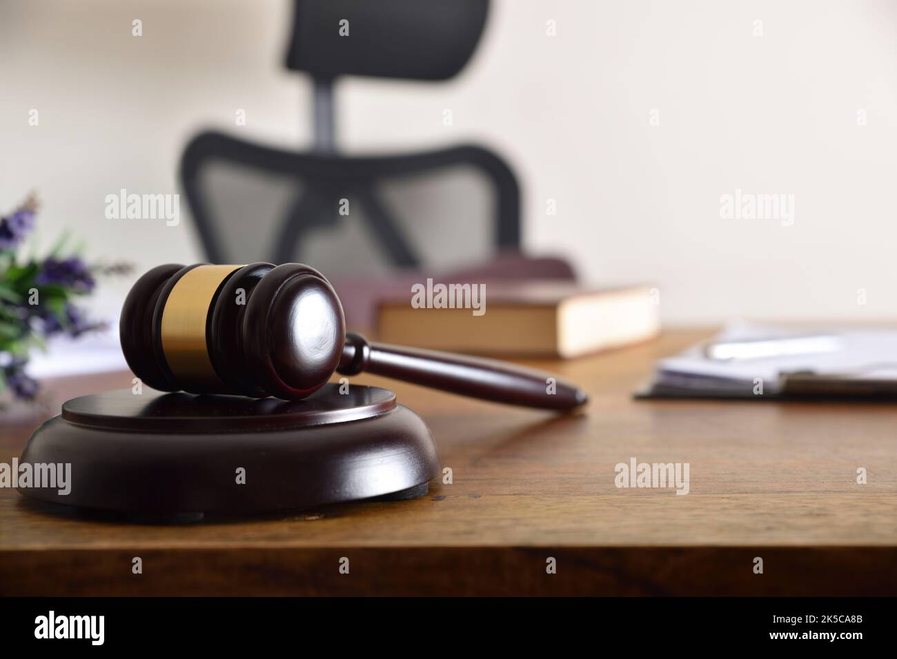 Gavel on the desk of a judge or lawyer with documents and books in the background. Front view Stock Photo