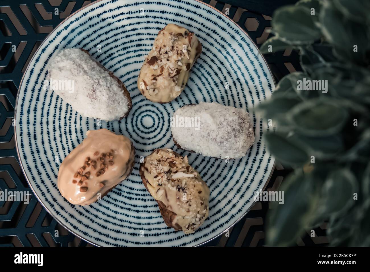 Mini eclairs with coconuts and hazelnuts on a plate in a cafe Stock Photo