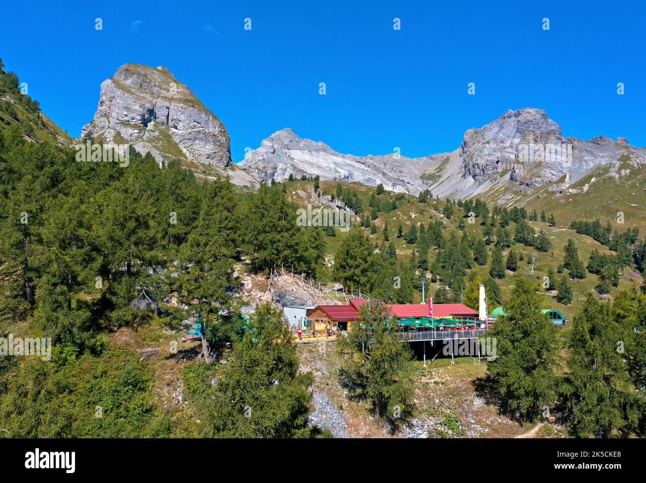 Mountain restaurant Jorasse in the larch forest, the peaks Six Armaille, Dent Favre and Pointe d'Aufalle of the Bernese Alps behind, Ovronnaz, Valais, Switzerland Stock Photo