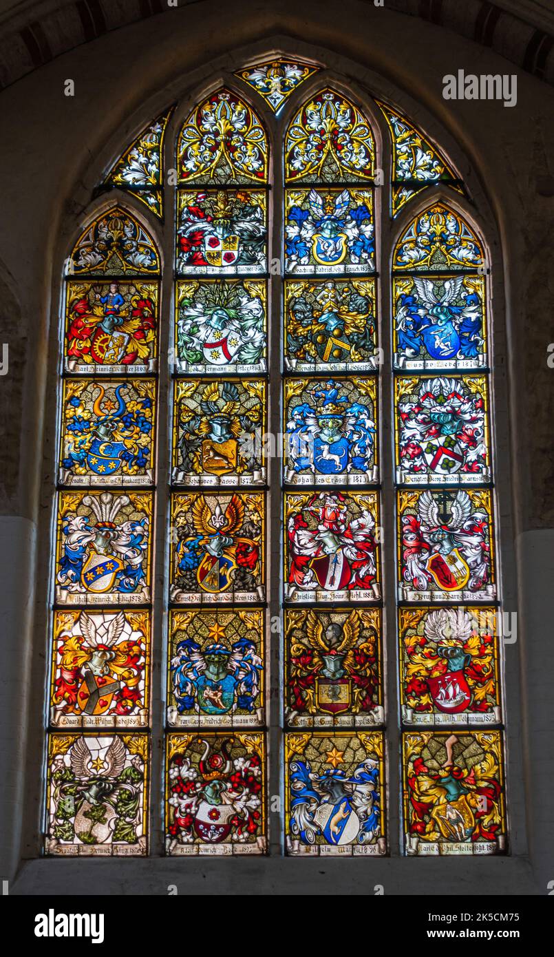 Germany, Lubeck - July 13, 2022: Heiligen Geist Hospital. Many coat of arms on stained window separting garden from entrance hall. Very colorful combi Stock Photo